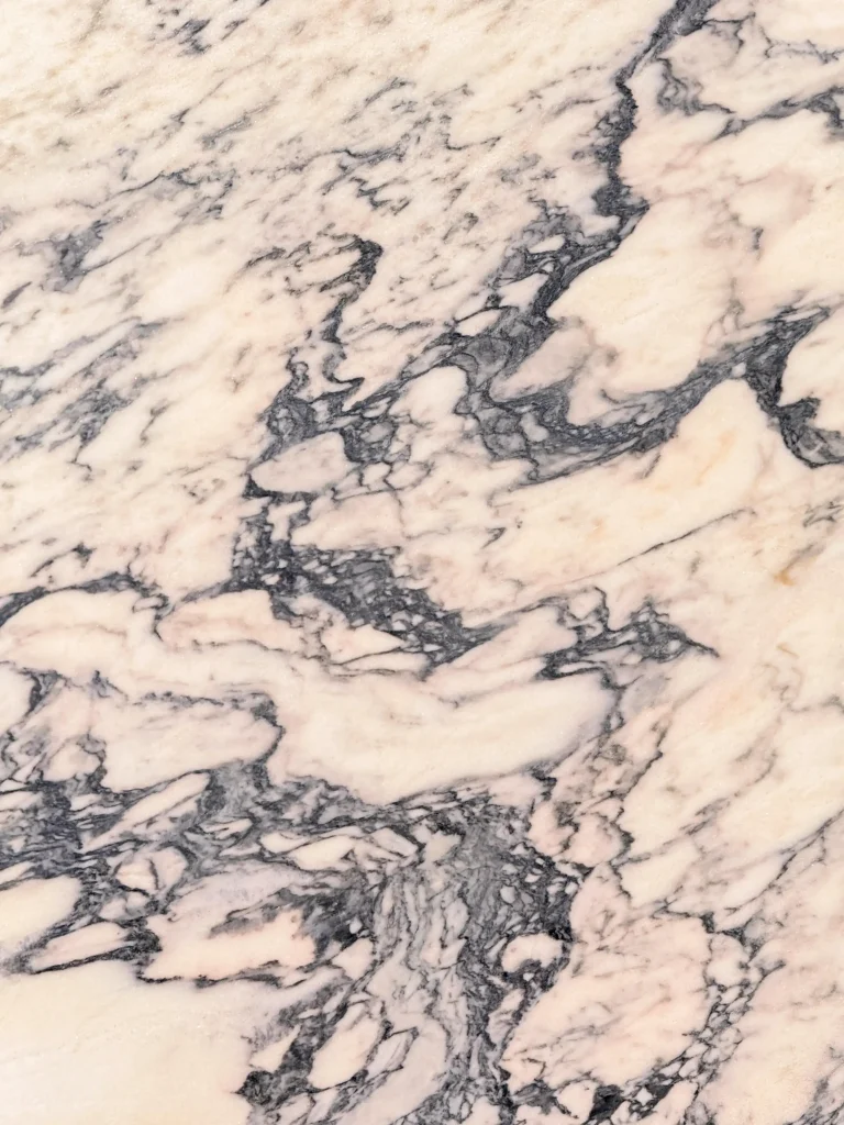 Calacatta Rosanoir Extra marble slab with a blush-pink and cream background, featuring dramatic dark grey veining, ideal for luxury kitchen worktops and bathroom interiors.